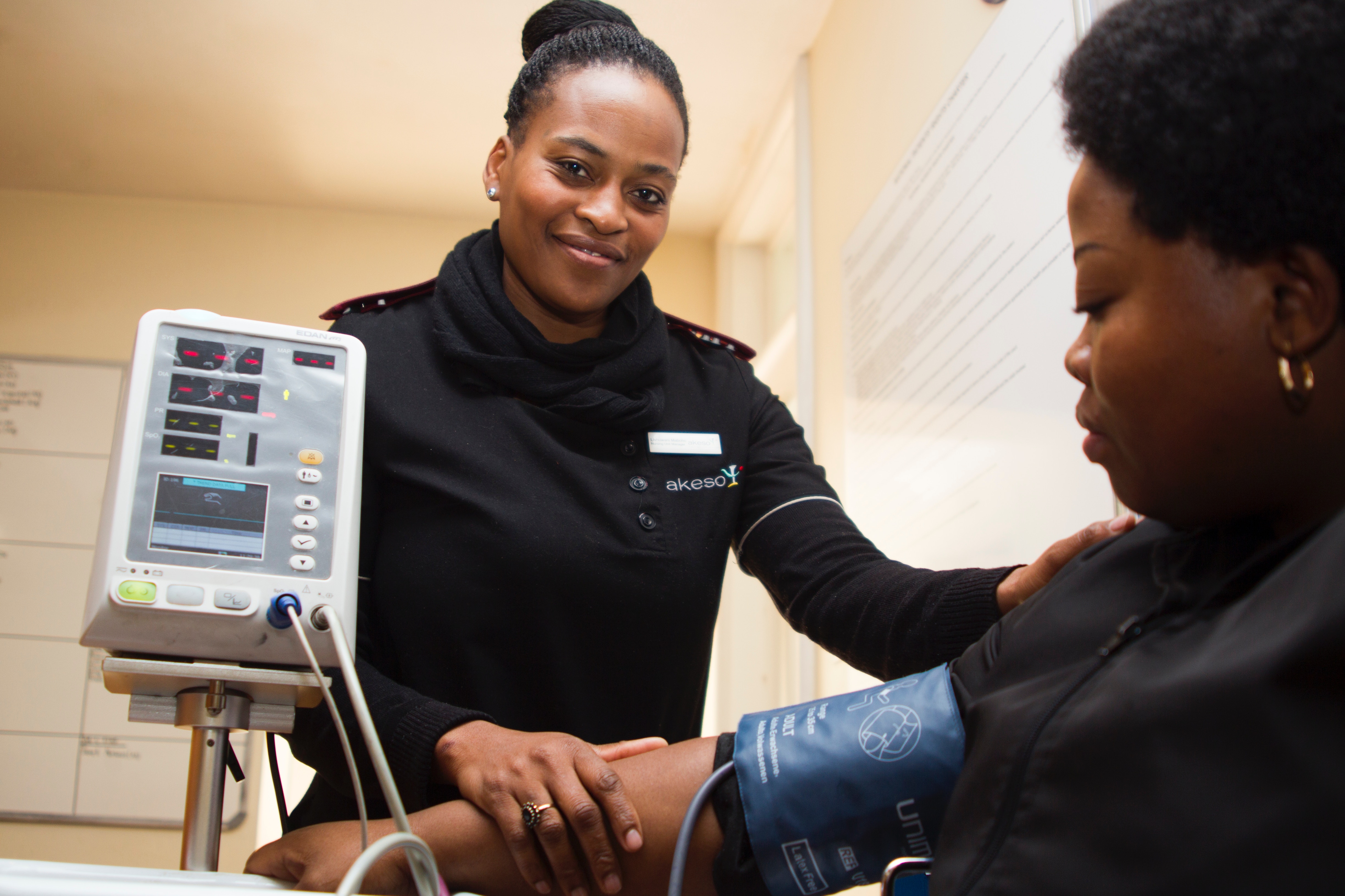 A smiling medical worker takes a patient's blood pressure.